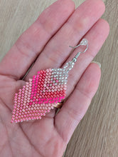 Charger l'image dans la galerie, Pink beaded earrings held in a hand on a wooden surface

